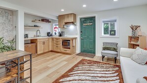 A modern kitchen with wooden cabinets, a microwave, and a green door. - Walk to The Oyster Bar: Chuckanut Dr Retreat! (Bow)