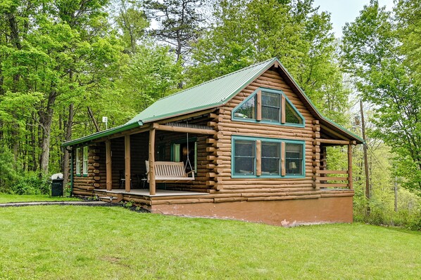 A log cabin with a porch, a covered deck, and a green roof. - Motorsports, Lake Days & Hikes! Cabin in Waterfall (Three Springs)