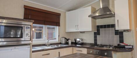 A modern kitchen with a built-in microwave, stainless steel range hood, and a wooden countertop.