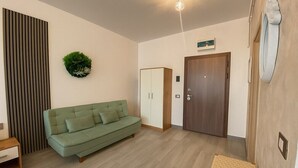 A modern living room with a green sofa, a wooden wardrobe, and a door. - Sasha Collection at N10 by Alezzi (Mamaia-Sat)