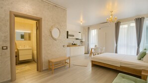 A modern, well-lit room with a bed, a bench, a dining area, and a kitchen in the background. - Sasha Collection at N10 by Alezzi (Mamaia-Sat)