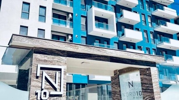 A modern multi-story building with a prominent 'Nord10' sign, featuring a mix of balconies and windows, and a stone facade at the entrance. - Sasha Collection at N10 by Alezzi (Mamaia-Sat)