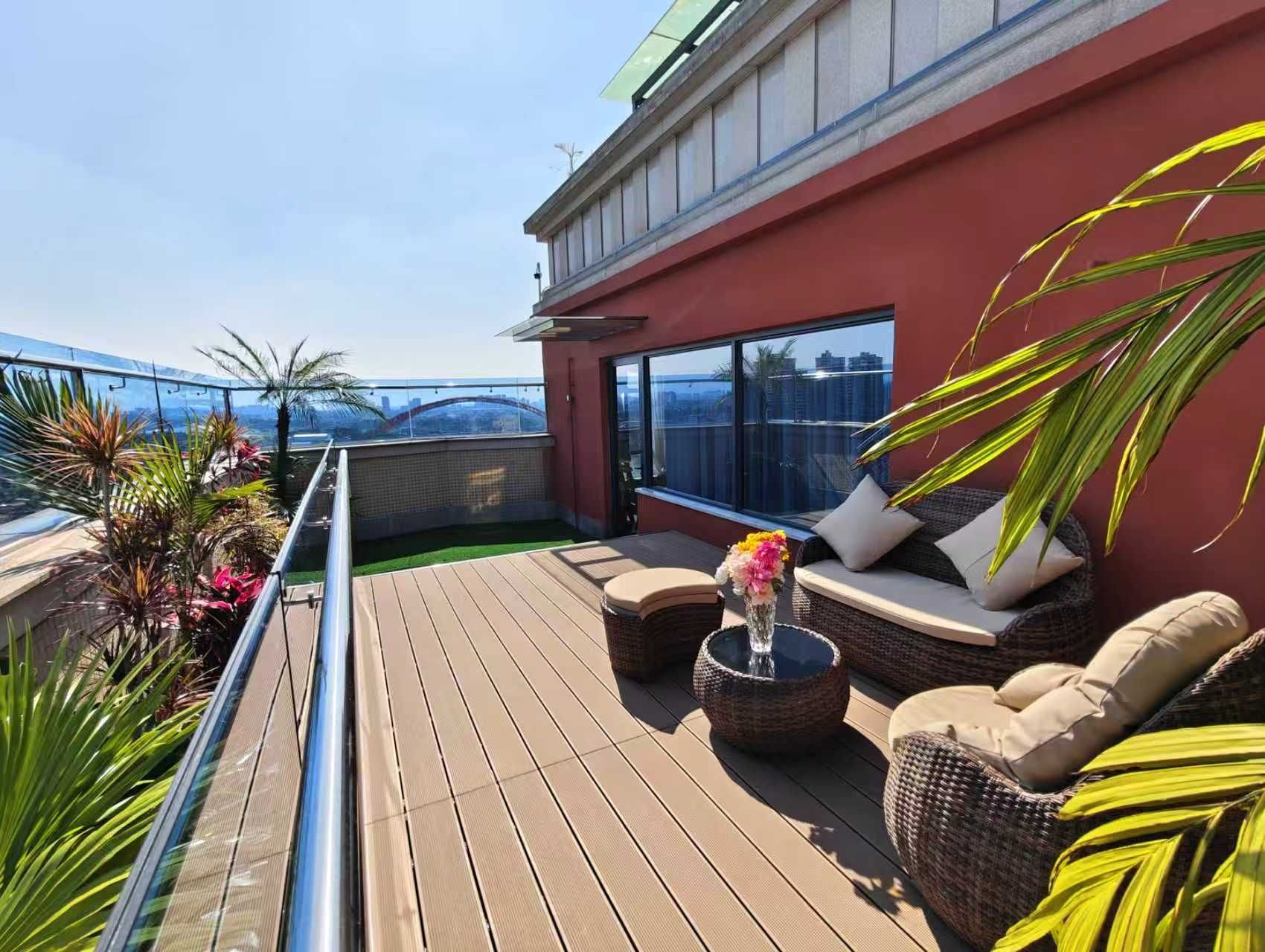 A rooftop terrace with a wooden deck, outdoor seating, and a view of the city skyline.