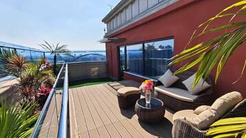 A rooftop terrace with a wooden deck, outdoor seating, and a view of the city skyline.