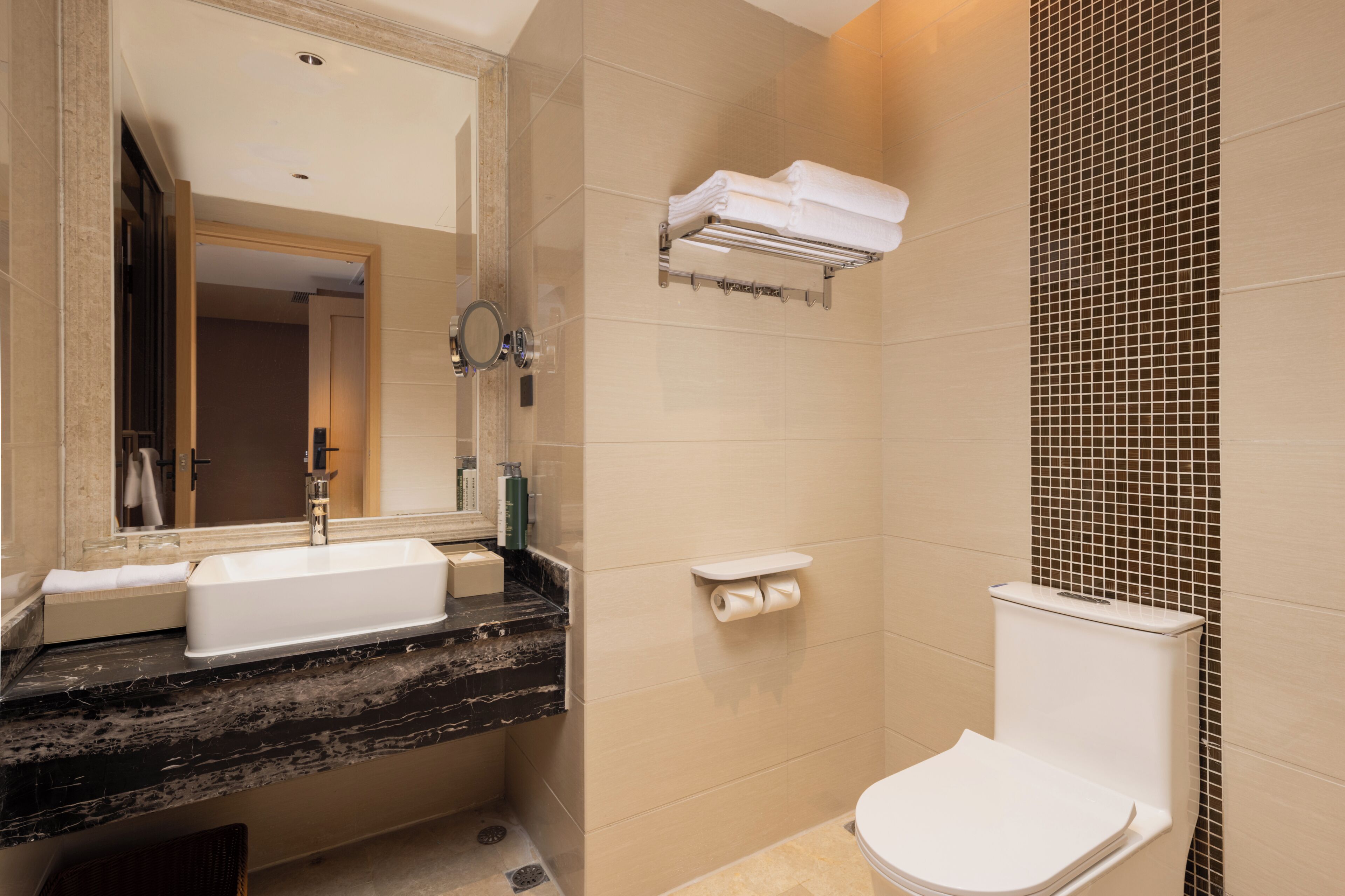 A bathroom with a sink, mirror, toilet, and towel rack.