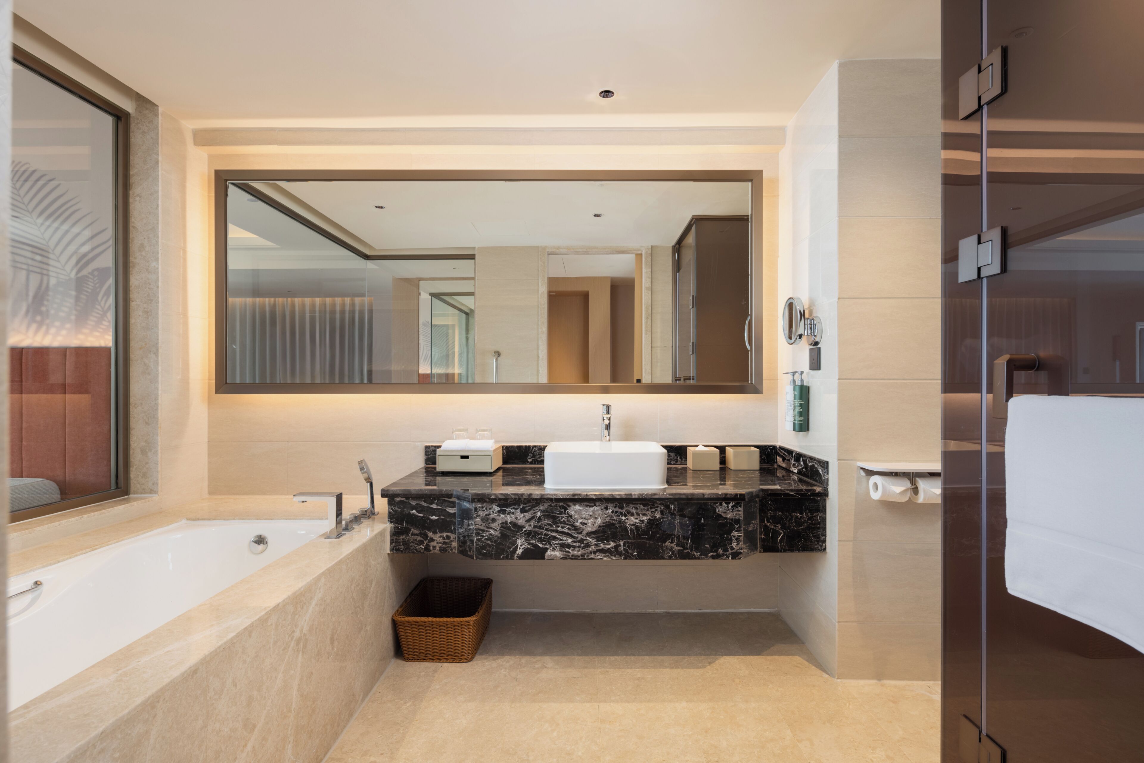 Un baño moderno con un espejo grande, una bañera, un lavabo y una zona de ducha.
