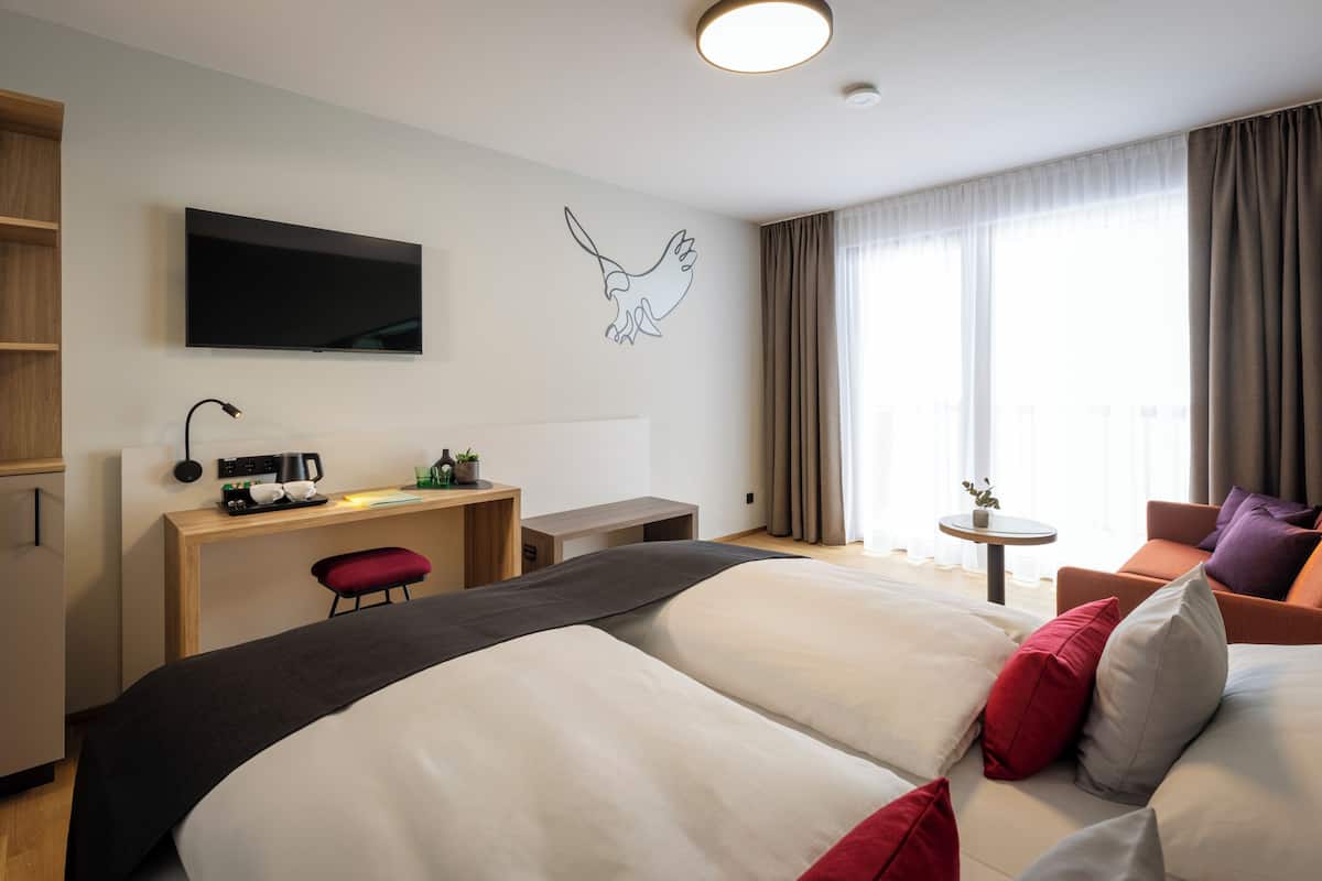 Een hotelkamer met een bed, een bureau, een televisie, een klein tafeltje en een stoel.