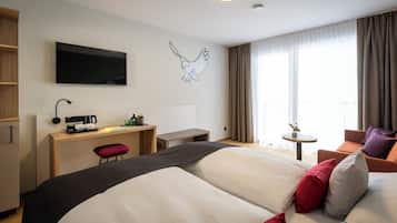 A hotel room with a bed, a desk, a TV, a small table, and a chair.