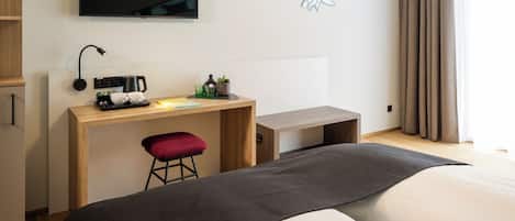 Une chambre d’hôtel équipée d’un lit, d’un bureau, d’une chaise, d’une télévision et d’une œuvre d’art accrochée au mur.