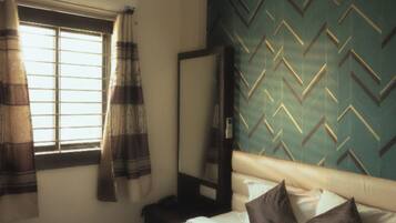 Una habitación de hotel con una cama, una ventana con cortinas, un espejo y una pared con un diseño geométrico.