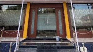 Η είσοδος ενός ξενοδοχείου με ένα στεγασμένο προθάλαμο, μια σειρά σκαλοπατιών που οδηγεί στις πόρτες και ένα μεταλλικό φράγμα μπροστά.