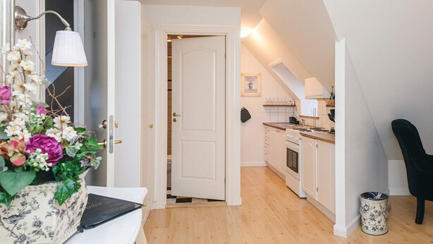 A modern kitchen with white cabinets, a wooden countertop, and a black chair. - 4 Star Holiday Home in Skanderborg (Skanderborg)