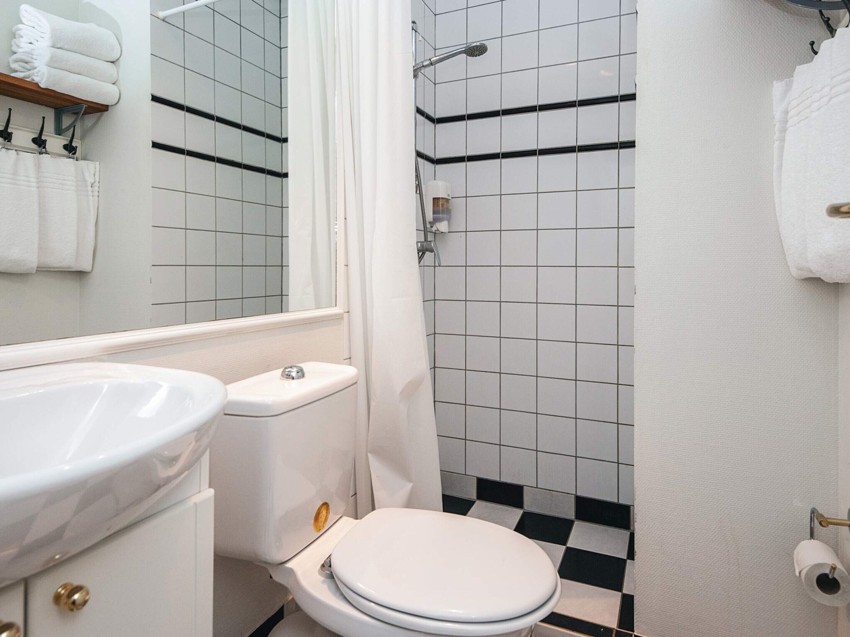 A bathroom with a white sink, toilet, and shower area.