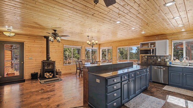 Una cocina amplia con una isla central, techo de madera y ventanas grandes.