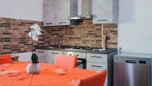 A compact kitchen with a brick backsplash, modern cabinets, a gas stove, and a dishwasher.