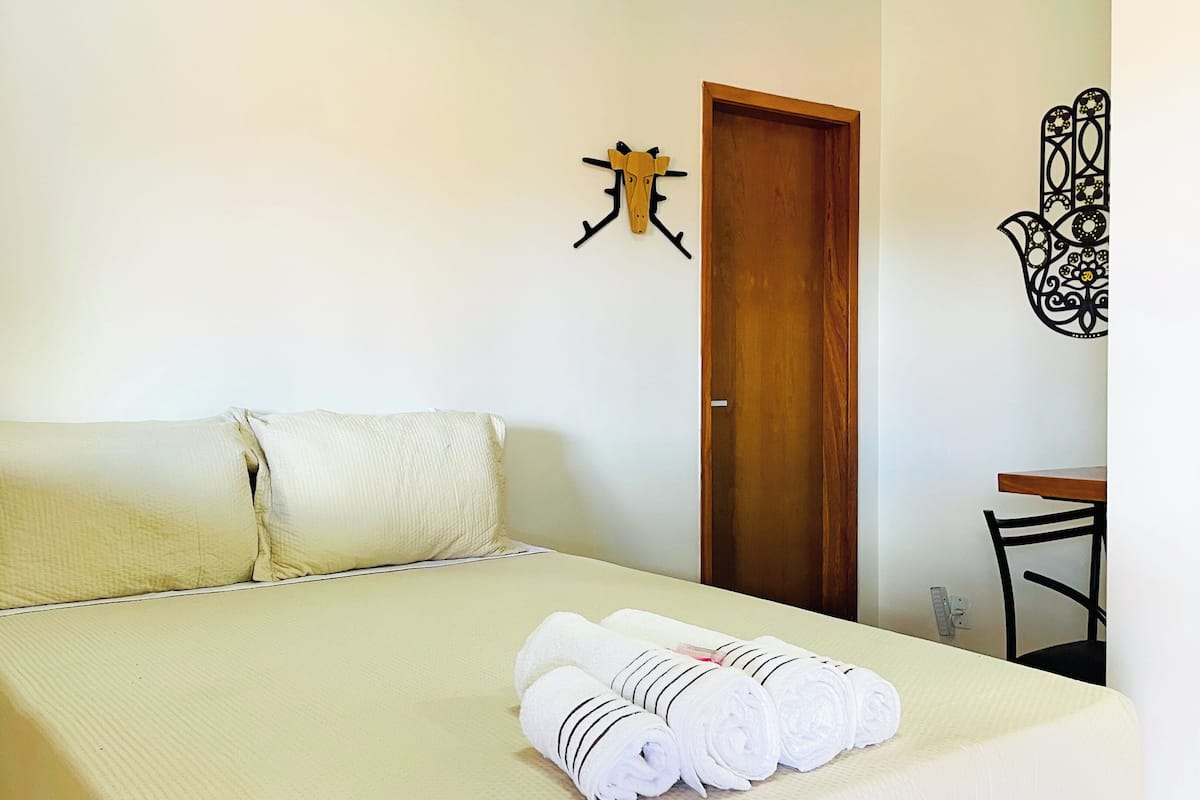 Ein Hotelzimmer mit einem Bett, einer Holztür, einem Schreibtisch und einer Wanddekoration.
