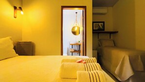 A hotel room with a bed, a bedside table, a chair, a hanging light fixture, and a framed picture on the wall. - Vila Bonita Guest House (Alto Paraíso de Goiás)