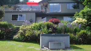 A two-story house with a balcony, a garage, and a well-maintained garden. - Waterfront Vacation Home -only for longer term stays(please contact for details) (Sechelt)