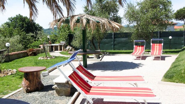A patio area with lounge chairs, a table, and a small garden. - Casa vacanze La Fonda - Glicine (Santo Stefano di Magra)