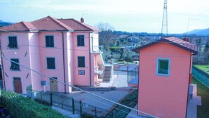 A pink building with a red roof, a staircase, and a small adjacent structure. - Casa vacanze La Fonda - Glicine (Santo Stefano di Magra)