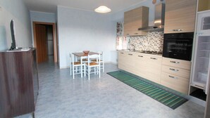 A modern kitchen with a dining area, featuring a built-in oven, a sink, and a light fixture above the table. - Casa vacanze La Fonda - Mimosa (Santo Stefano di Magra)