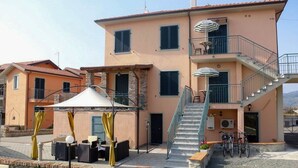 A two-story building with a staircase, outdoor seating area, and bicycles parked outside. - Casa vacanze La Fonda - Mimosa (Santo Stefano di Magra)