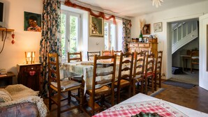 Een eetruimte met een tafel voor vier personen, houten stoelen, een kroonluchter en een trap naar een hoger niveau.