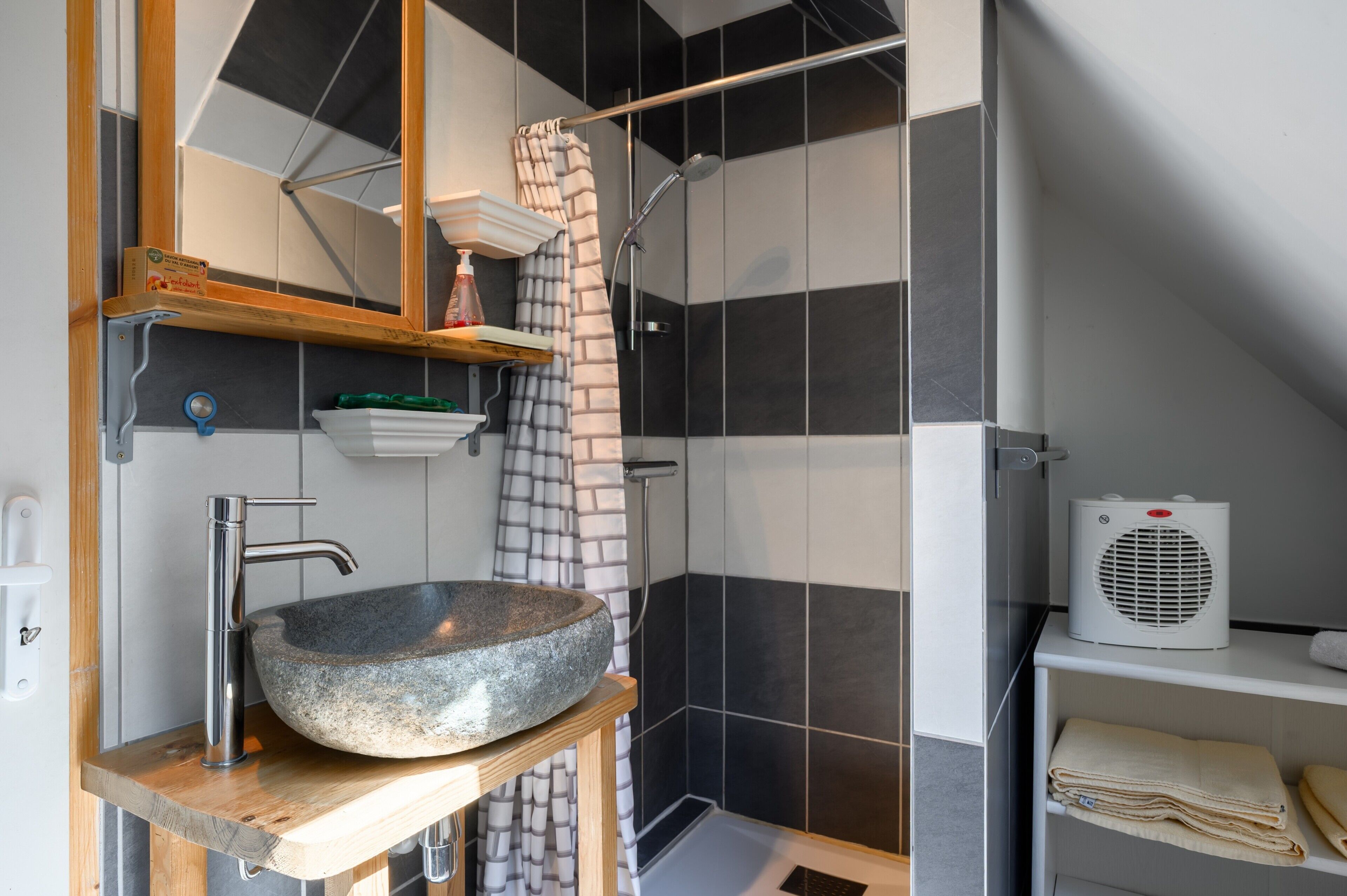A bathroom with a stone basin, a shower, and a towel rack.