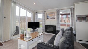 Una sala de estar moderna con televisor de pantalla plana, chimenea, sofá y comedor con mesa de madera.