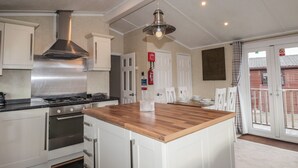 Una cocina moderna con armarios blancos, extractor de acero inoxidable y una isla central.