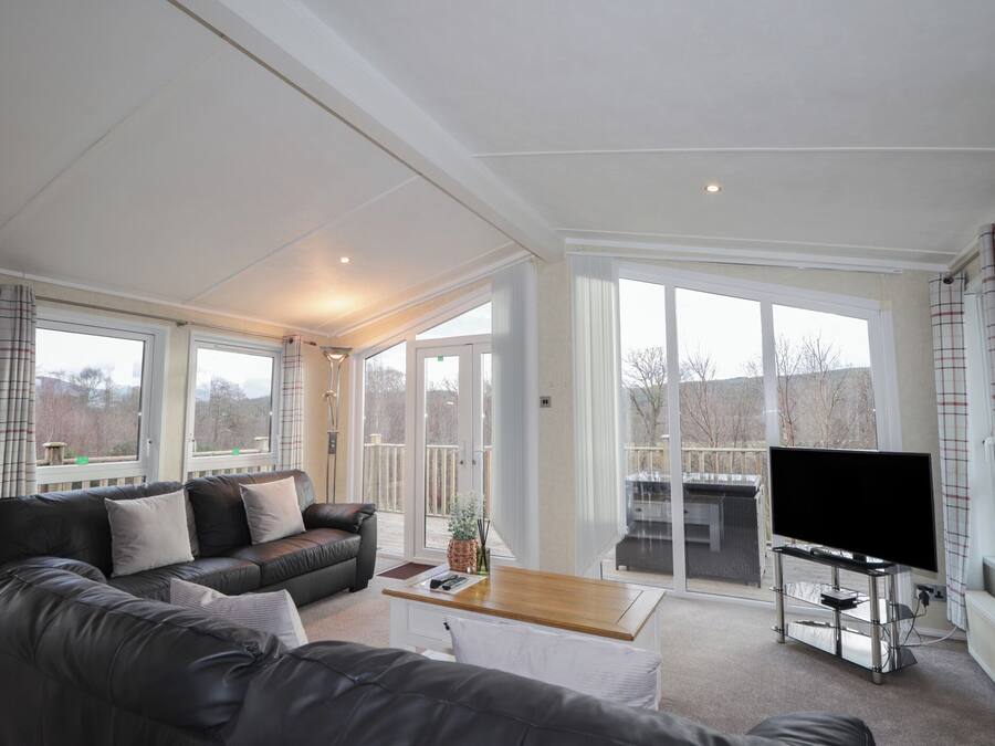 A modern living room with a leather sofa, a coffee table, and a flat-screen TV on a stand.