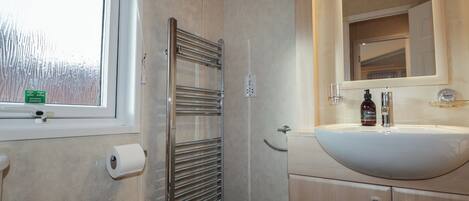 A bathroom with a white sink, a mirror, and a towel dispenser.