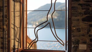 Ein Fenster mit einem metallenen Zierdekor und Blick auf eine Berglandschaft.