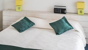 A bed with two pillows, a bedside table with a radio, and two wall-mounted lamps. - Le Lido Apartment – Beach, Pool, Parking, Sea View, Wi-Fi, Air Conditioning (Cagnes-sur-Mer)