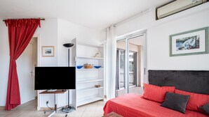 A bedroom with a bed, a TV, a wardrobe, a sliding door to a balcony, and a painting on the wall. - Le Lido Apartment – Beach, Pool, Parking, Sea View, Wi-Fi, Air Conditioning (Cagnes-sur-Mer)