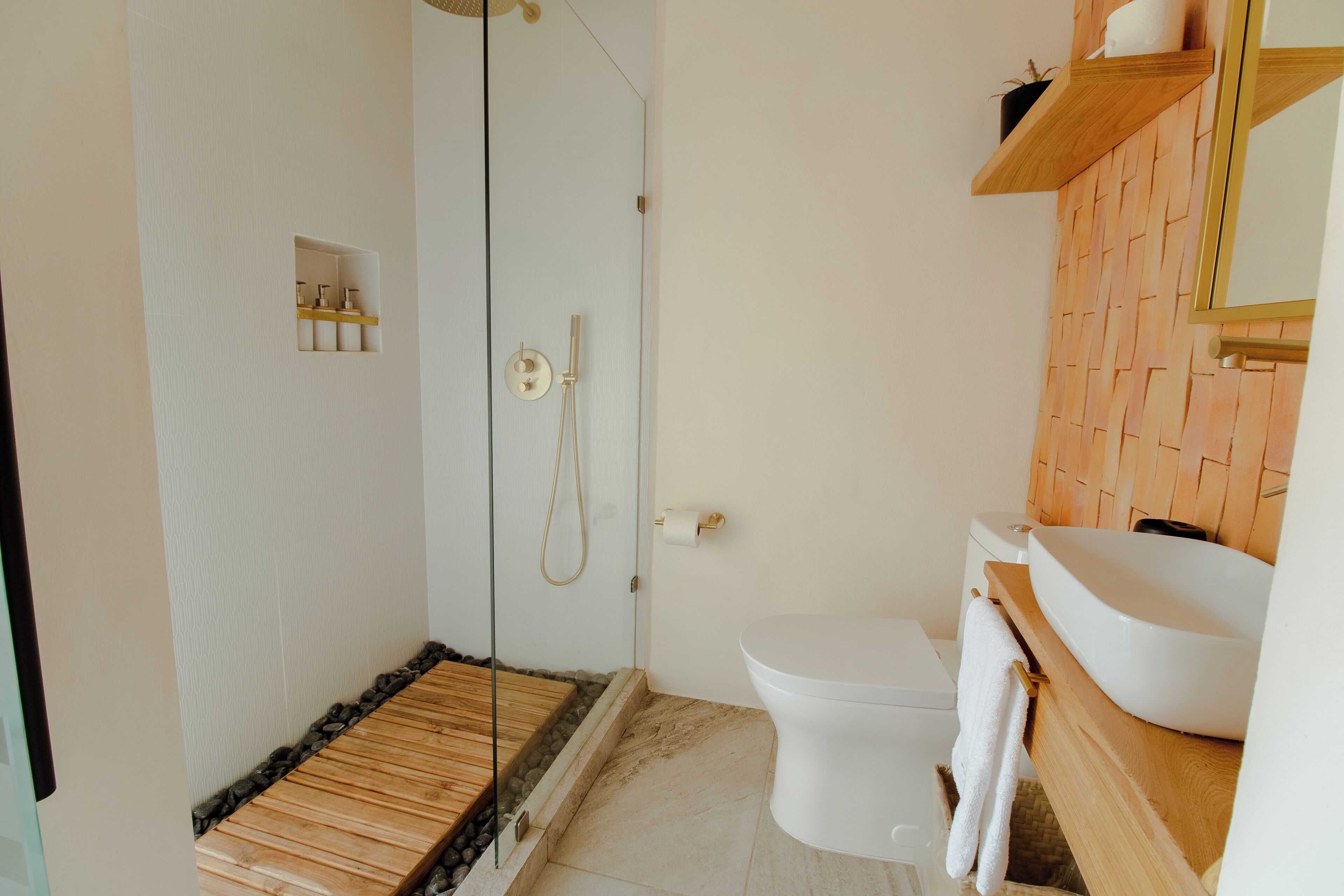 A modern bathroom with a glass-enclosed shower, a white toilet, and a wooden vanity with a sink.