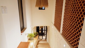 A staircase with a woven light fixture, a wooden bench, and a patterned wall. - Bernardino Hotel Boutique (Guanajuato)