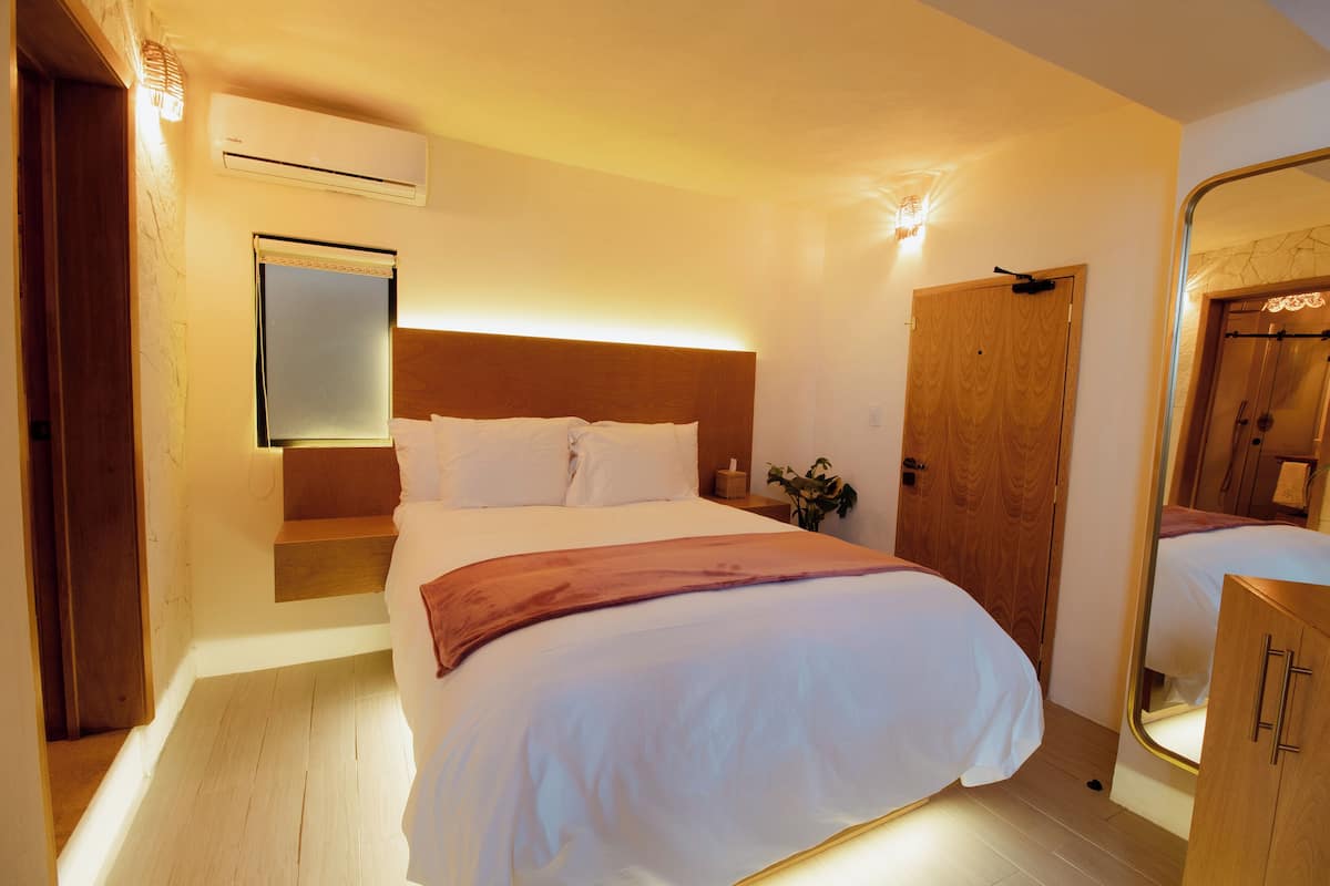 Ein Schlafzimmer mit einem großen Bett, einem Holzkopfende, einem Nachttisch, einem Spiegel und einem Holzschrank.