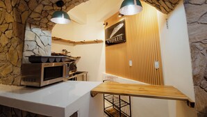 A kitchen with a stone wall, wooden paneling, a microwave, and hanging lights. - Bernardino Hotel Boutique (Guanajuato)