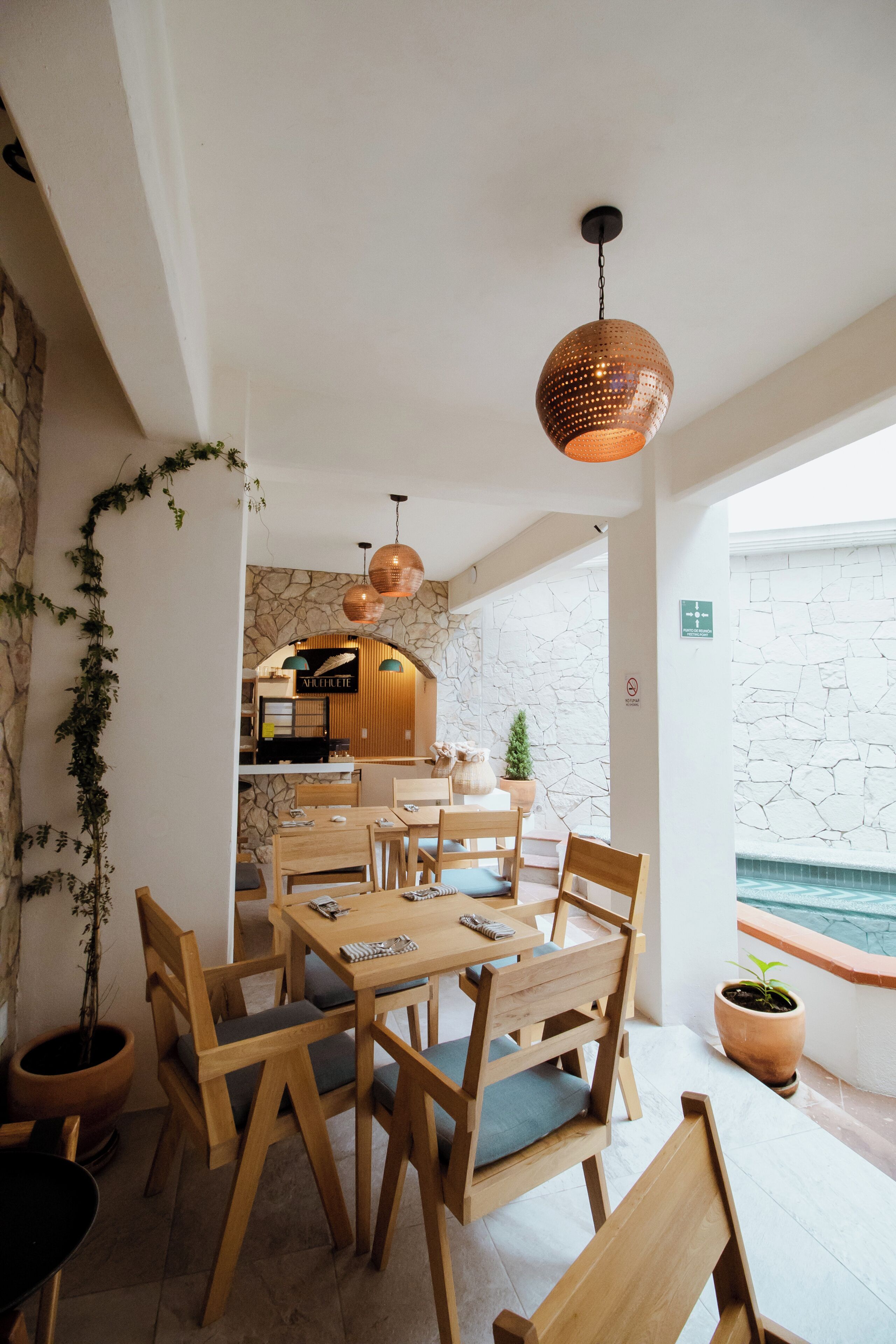 A dining area with wooden furniture and hanging copper pendant lights.