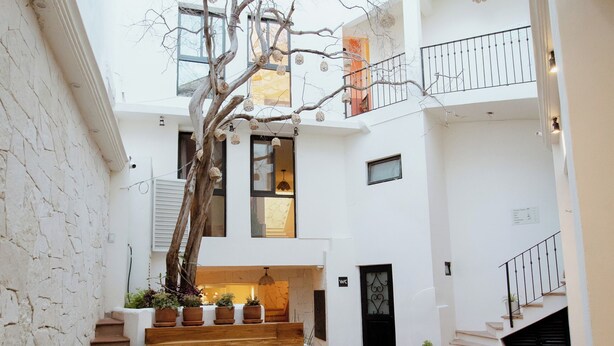 A modern indoor pool area with a tree, stairs, and a view of the upper floors. - Bernardino Hotel Boutique (Guanajuato)