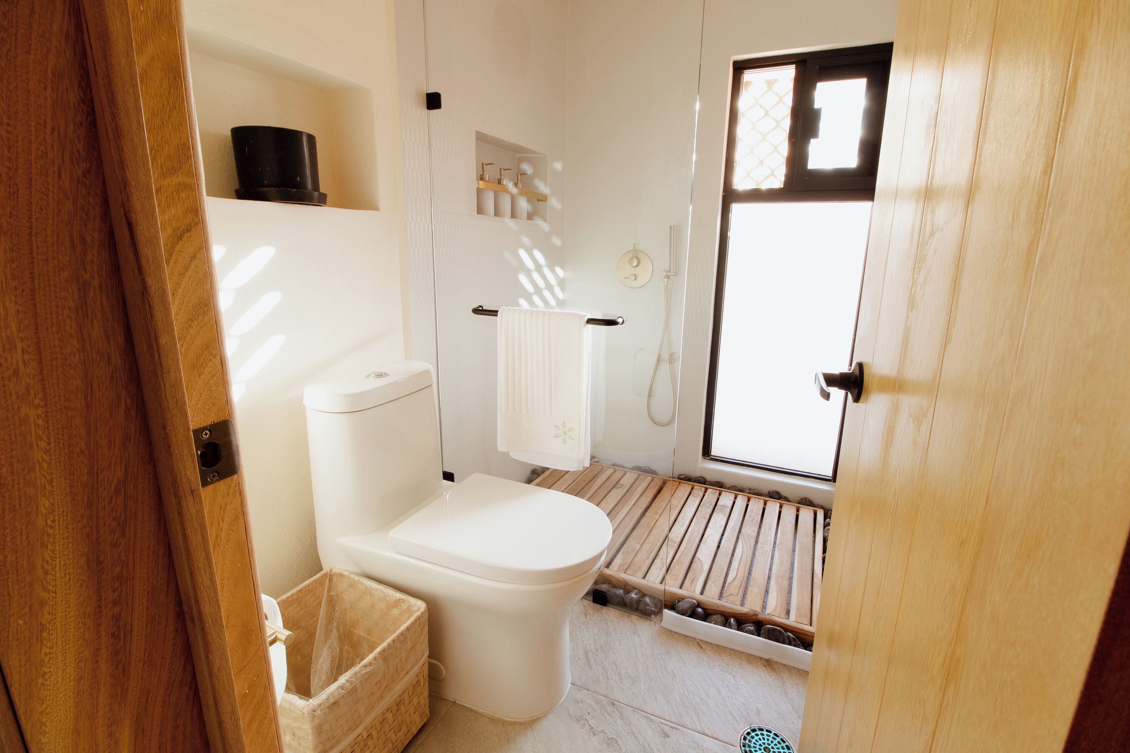 A bathroom with a toilet, a sink, a towel rack, and a window.