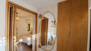 A bedroom with a wooden wardrobe, a large mirror, and a bed with a white headboard. - Bernardino Hotel Boutique (Guanajuato)
