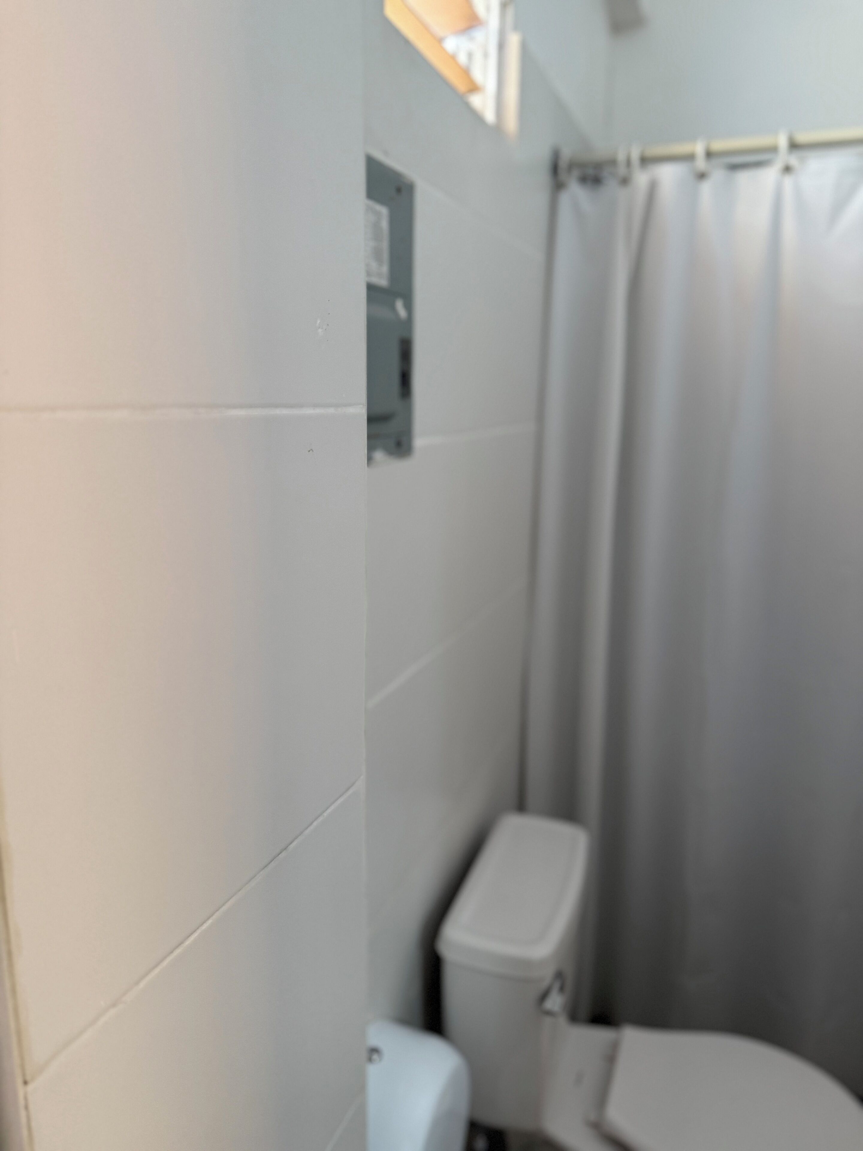 A bathroom with white tiles, a toilet, and a shower curtain.