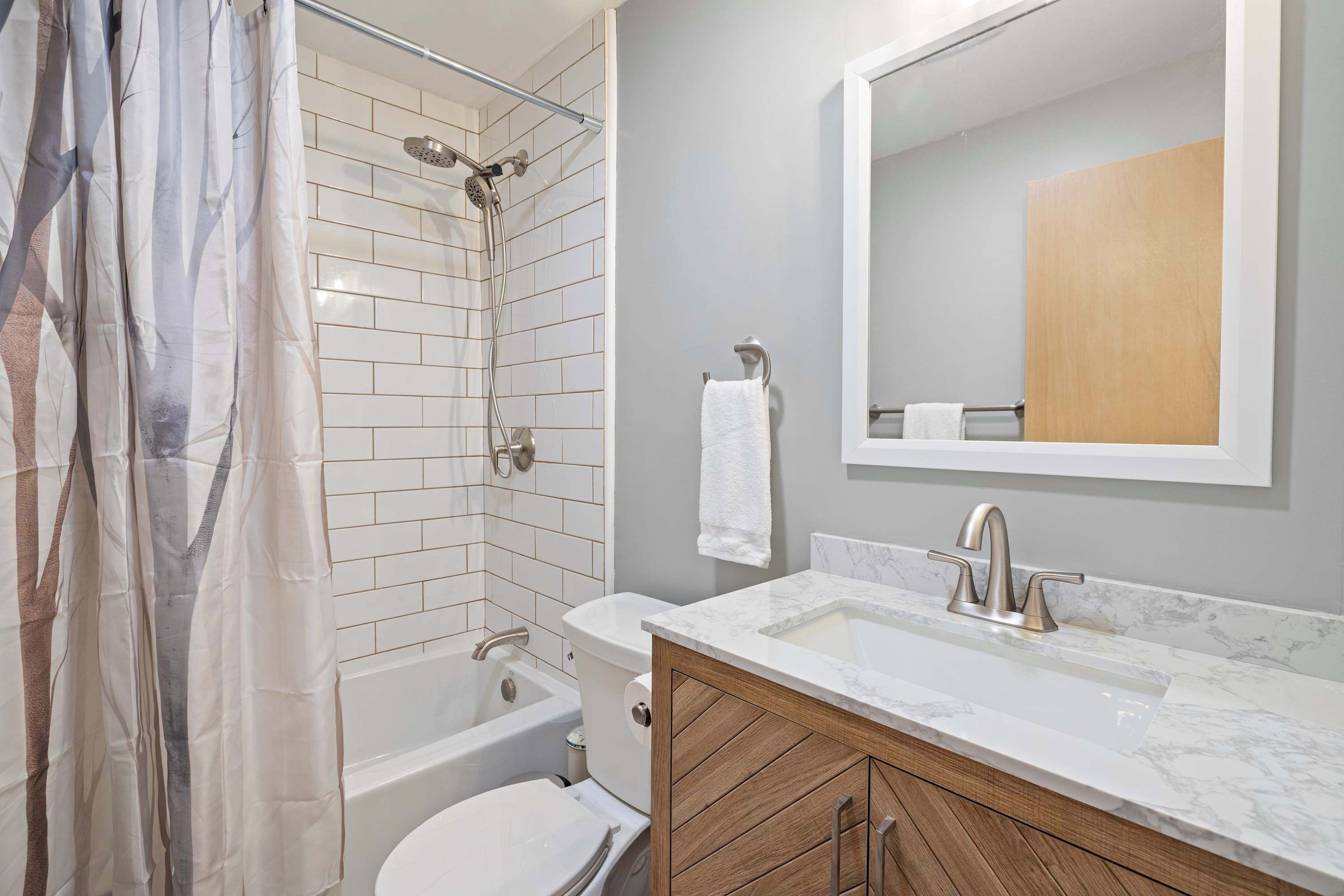 A modern bathroom with a shower, toilet, and sink.
