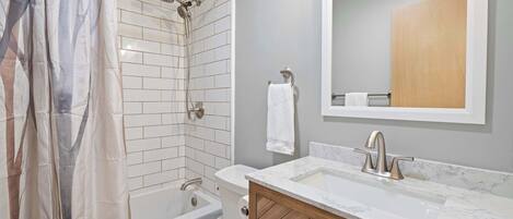 A modern bathroom with a shower, toilet, and sink.