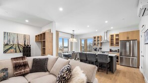 A modern kitchen with a stainless steel refrigerator, wooden cabinets, and a dining area with chairs and a table. - Family Ski-In/Ski-Out at South Face Village (Ludlow)