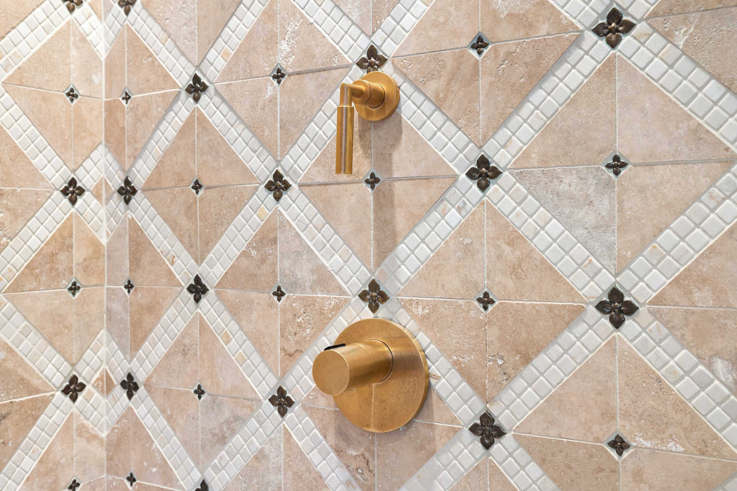 Un baño con suelo de baldosas en patrón de rombos y grifo dorado.