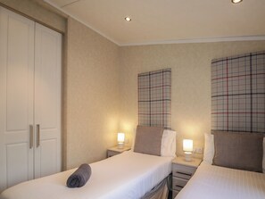 A hotel room with two beds, a wardrobe, and a headboard with a plaid pattern. - Tiree Lodge (Fort William)