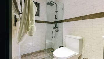 A modern bathroom with a glass-enclosed shower, a white toilet, and a wooden accent strip on the wall.